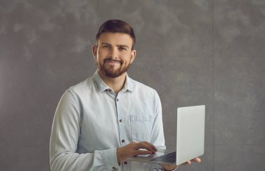 Stüdyo duvarında dizüstü bilgisayarı tutan kendine güvenen bir iş adamı.