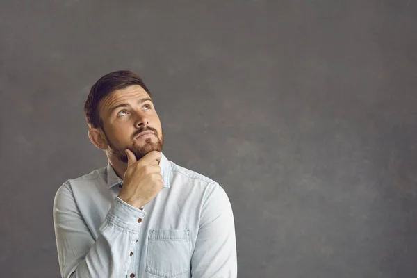 Pensieve bedachtzame blanke man met baard aanraken kin kijkt omhoog studio schot — Stockfoto