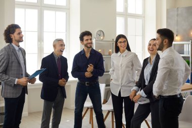 Genç ve mutlu bir iş ekibi ofiste olgun bir yöneticiyle eğlenceli bir konuşma yapıyor..