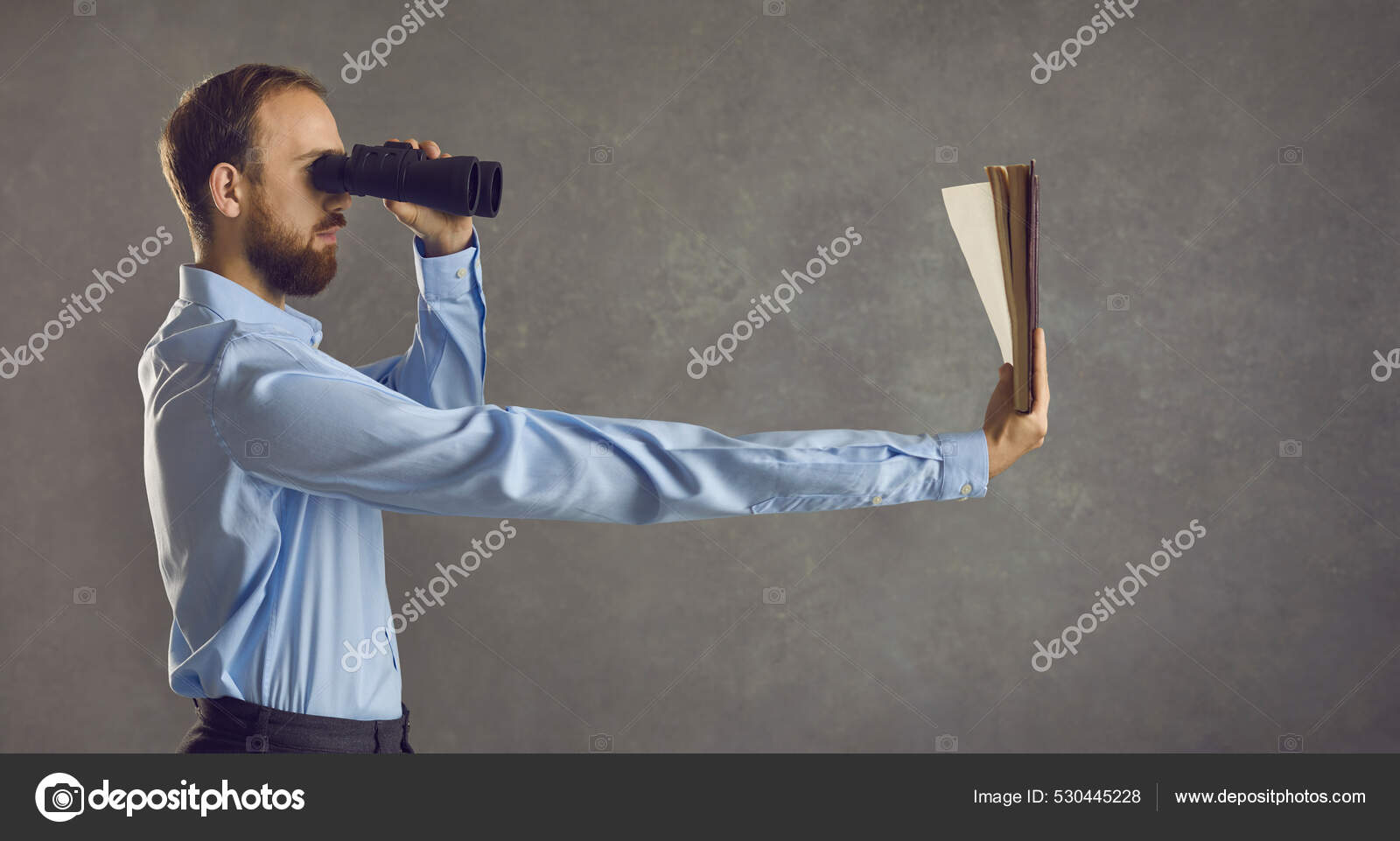 一个拿着双筒望远镜的年轻人的侧视图，他正手挽着一长臂看书——图库图片© lacheev #530445228, image size:1600x961