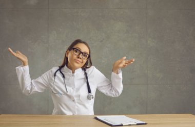 Şaşırmış, beceriksiz genç doktor, hemşire ya da stajyer omuz silkiyor.