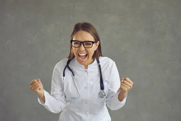 Счастливая возбужденная молодая женщина-врач кричит Да празднует свой профессиональный успех — стоковое фото