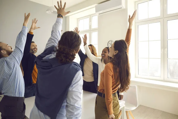 Equipe de funcionários diversos felizes levantando as mãos votando por uma boa sugestão em reunião corporativa — Fotografia de Stock
