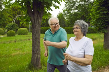 Spor yaparken parkta koşu yapan mutlu yaşlı çift.