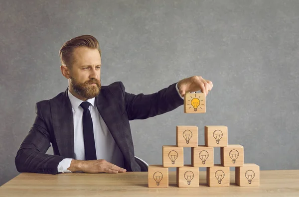 Empresario encuentra solución y pone último cubo con bombilla en la parte superior de su pirámide de ideas — Foto de Stock