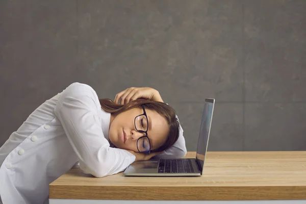 Cansado trabajador de oficina agotado durmiendo sentado en el escritorio cerca de la computadora portátil —  Fotos de Stock