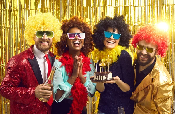 Jovens amigos de moda disco sorridente de pé com bolo de aniversário e champanhe — Fotografia de Stock