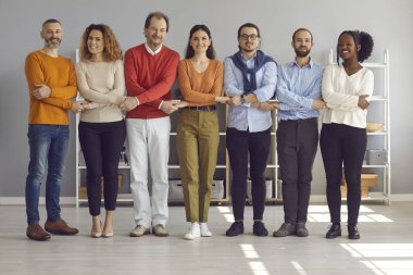 Mutlu çok ırklı insanlar el ele tutuşup sıraya dizilmiş kameralara bakıyorlar.