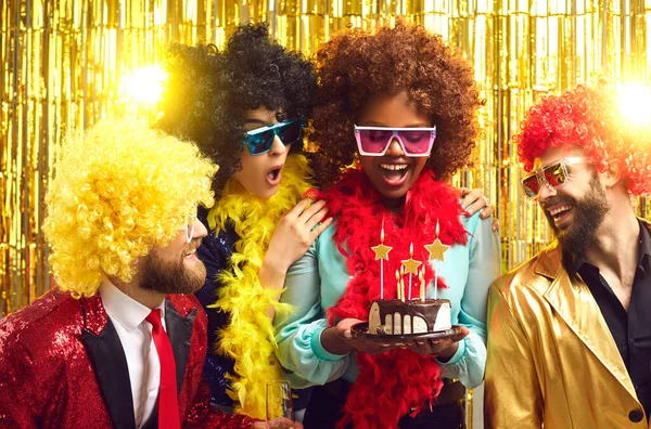 Glückliche multiethnische Menschen in Party-Perücken und BH überreichen Kuchen an Kumpel — Stockfoto