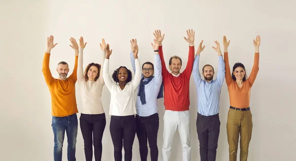 Feliz equipo de negocios diverso levantando las manos de pie sobre fondo de estudio beige claro —  Fotos de Stock