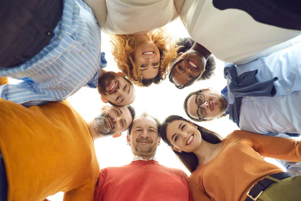 Niedrigwinkel-Porträt eines vielseitigen Teams glücklicher Menschen, die sich in einem Unternehmenstreffen zusammendrängen — Stockfoto