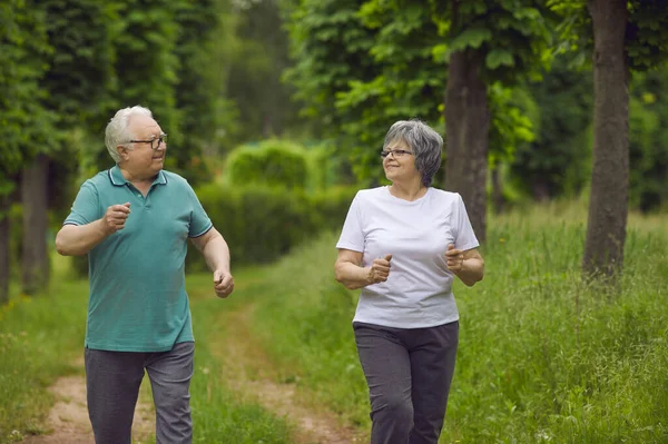 快乐的老夫妇一边慢跑一边在公园里一起享受积极的健身锻炼 — 图库照片