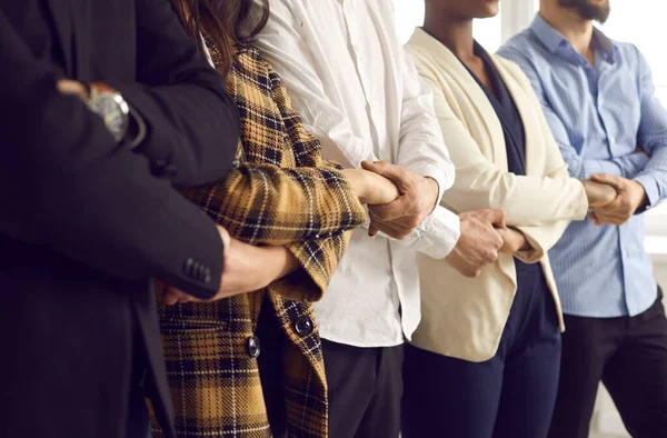 Vystřižený záběr různorodého týmu podnikatelů, kteří stojí při sobě a drží se za ruce — Stock fotografie