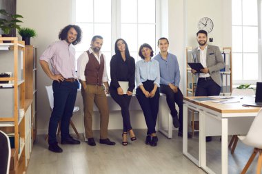 Modern ofisin penceresinde başarılı bir yaratıcı profesyonel iş ekibi duruyor.