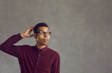 Gri fotokopi alanının üzerinde kafasını kaşıyan Afrikalı Amerikalı adamı sorgulamak