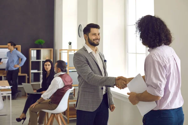 Dos empresarios felices o compañeros de oficina se dan la mano mientras se reúnen en una reunión de negocios — Foto de Stock
