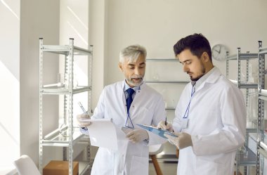 Bilim laboratuarı yöneticisi ve asistanı birlikte deney sonuçlarını tartışıyor.