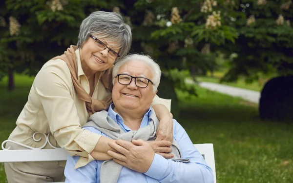 Πορτρέτο του ευτυχισμένου ηλικιωμένου ζευγαριού χαμογελώντας και κοιτάζοντας κάμερα στο πράσινο καλοκαιρινό πάρκο — Φωτογραφία Αρχείου