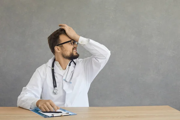 Dorosły rozczarowany przepracowany lekarz czuje wstyd i stres z ręki na głowę — Zdjęcie stockowe