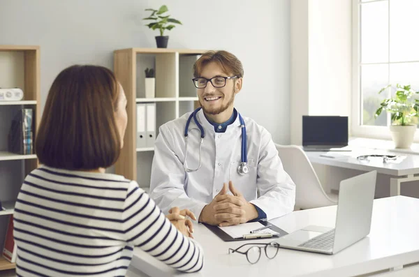 Medico felice che parla con il suo paziente seduto a tavola nel suo ufficio, clinica o ospedale — Foto Stock