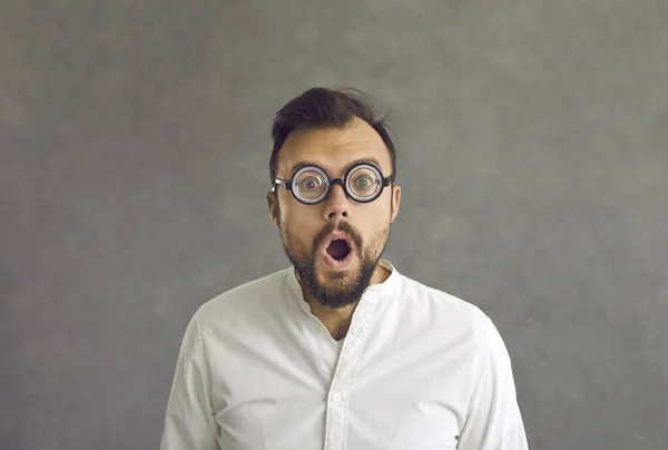 Portret van grappige geschokte man ronde optische bril staan op grijze achtergrond — Stockfoto