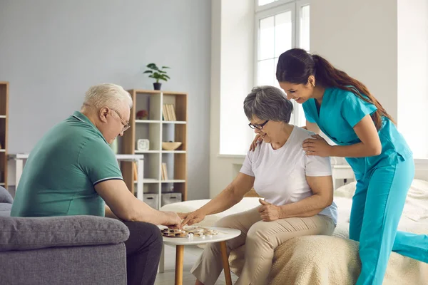 Heureux vieil homme et femme retraités ont plaisir à jouer à des jeux de société dans la maison de soins infirmiers. — Photo