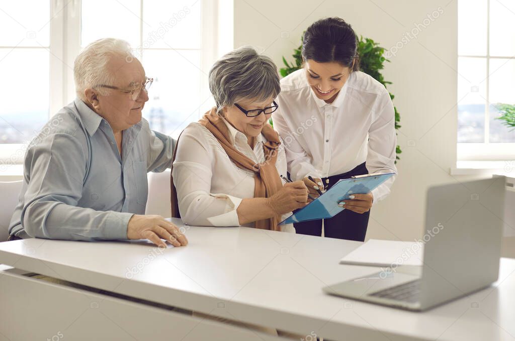 Senior couple sign a legal paper contract in the office during a meeting with a financial adviser.