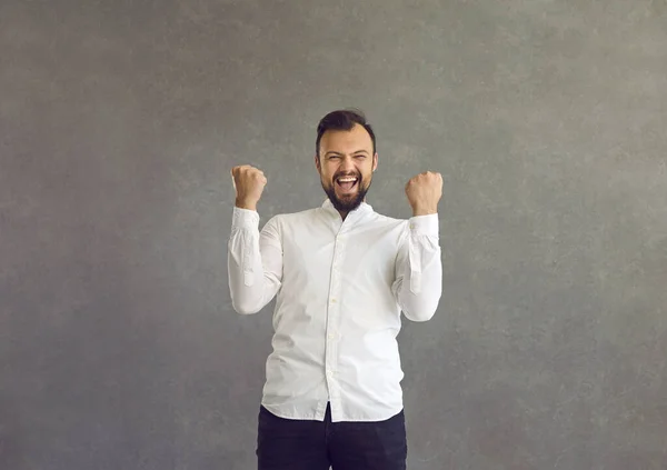 Halve lengte portret van vrolijke juichende man met gebalde vuist staan op grijze muur — Stockfoto