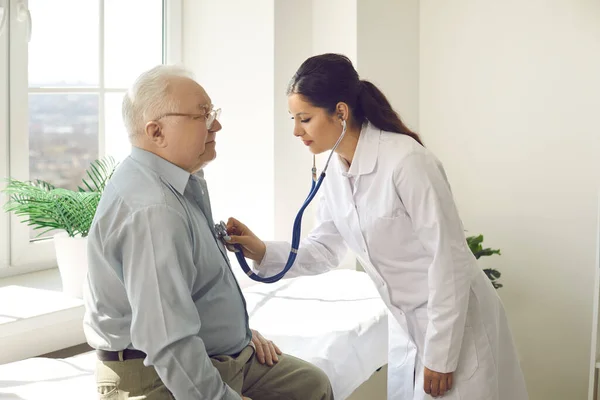 Doctor with stethoscope listen elderly male patient heartbeat at hospital ward