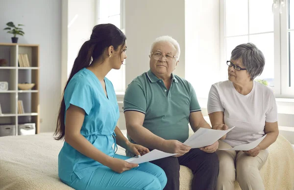 Un soignant professionnel aide les patients âgés à comprendre et à remplir le contrat de soins à domicile — Photo