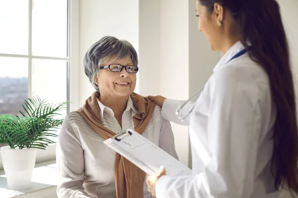 Senior woman looking at doctor and listening to her advice with happy smile on face — Foto Stock
