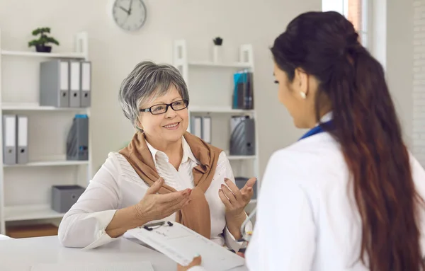 Femme âgée joyeuse parlant à son médecin lors de sa visite à la clinique ou à l'hôpital — Photo