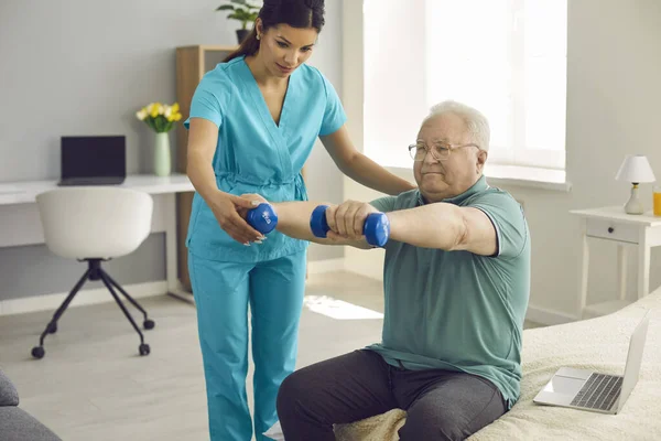 Physiotherapist or home care nurse helping senior patient do rehabilitation exercise