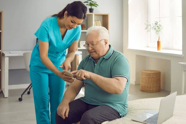 Travailleur de la santé enseignant à son patient aîné à utiliser l'application de santé sur son téléphone mobile — Photo