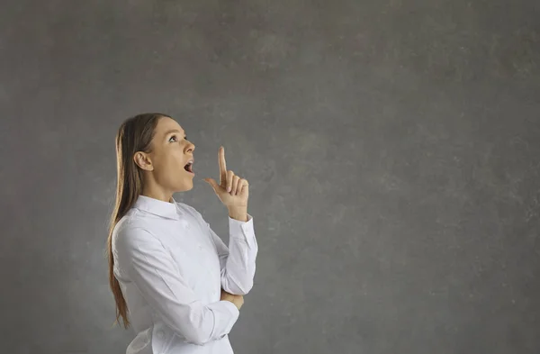 Woman raises her index finger up as a sign that a bright idea or thought has occurred to her. — Stock Photo, Image