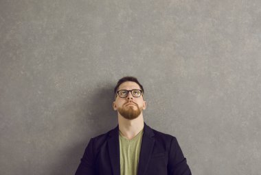 Düşünceli ve şüpheli bir ifadeye sahip ciddi bir beyaz adam kafasının üzerinden yukarı bakıyor..