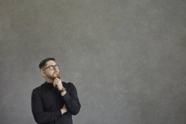 Gri beton arka planda dalgın yüz ifadesi olan kafası karışmış bin yıllık beyaz bir adam..