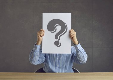 Unknown business man hiding his face behind a sheet of paper with a question mark