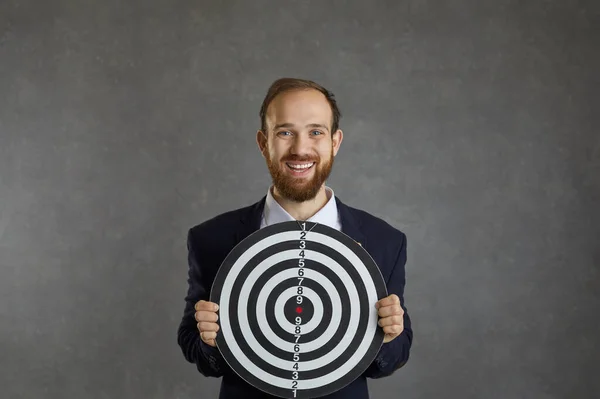 Happy smiling young man holding a shooting target that represents a business goal — Foto de Stock