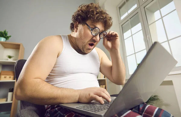 Surprised shocked funny fat man in pajamas reads amazing news on laptop — 图库照片