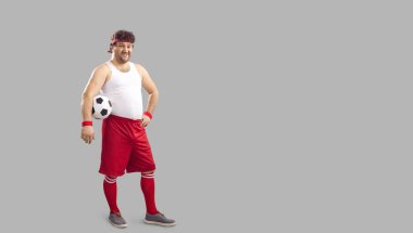 Happy chubby soccer player holding ball and smiling standing on copy space background