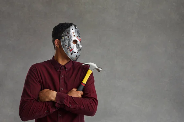 Black man in scary mask holding hammer and looking away on grey copy space background — Foto de Stock