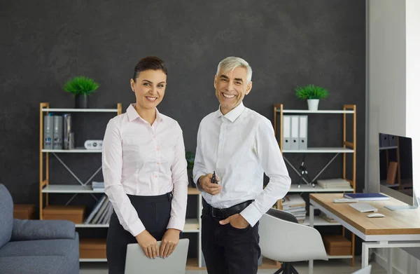 Senior male boss and young female secretary standing in office portrait — Stok fotoğraf