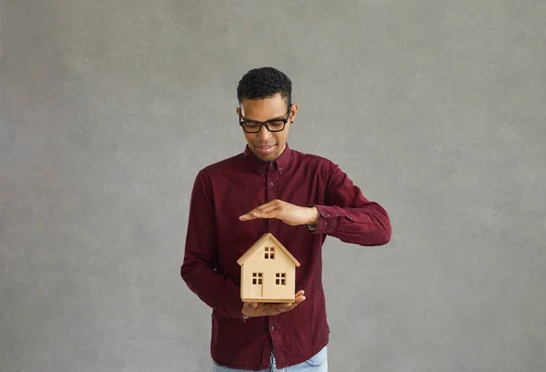 Hombre afroamericano joven agente de bienes raíces con techo cubierta de la casa con la mano —  Fotos de Stock