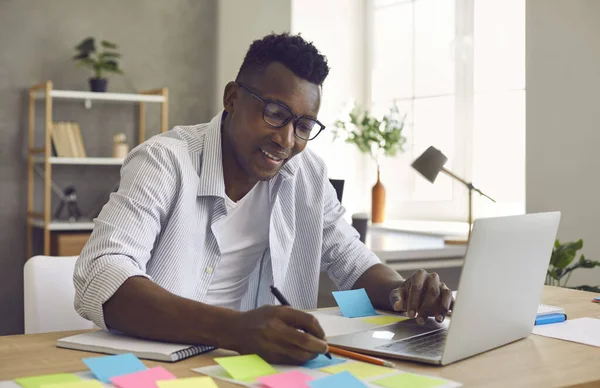 Afro-Américain écrit des notes sur les autocollants tout en développant un projet d'entreprise dans le bureau. — Photo