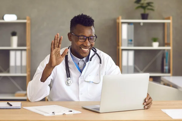 Dunkelhäutige freundliche Ärztin führt eine Online-Konsultation mit einem Patienten per Videoanruf durch. — Stockfoto