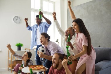 Bir grup genç taraftar televizyonda futbol seyrediyor, bağırıyor ve favori takımı destekliyorlar.