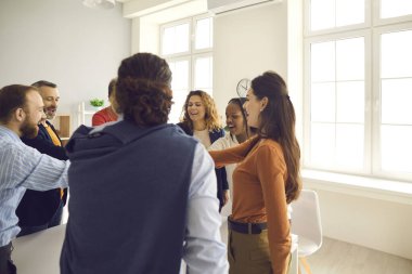 Mutlu iş arkadaşları ve dostlardan oluşan bir takım daire oluşturup el ele tutuşuyorlar.