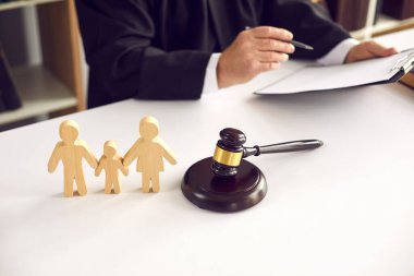Tahta aile figürleri ve cezayı imzalayan bir yargıcın arka planındaki tokmak..