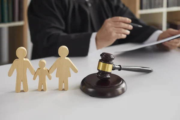 Figuras de madera de la familia con el niño y el martillo en el fondo del juez que conduce el proceso de divorcio. — Foto de Stock